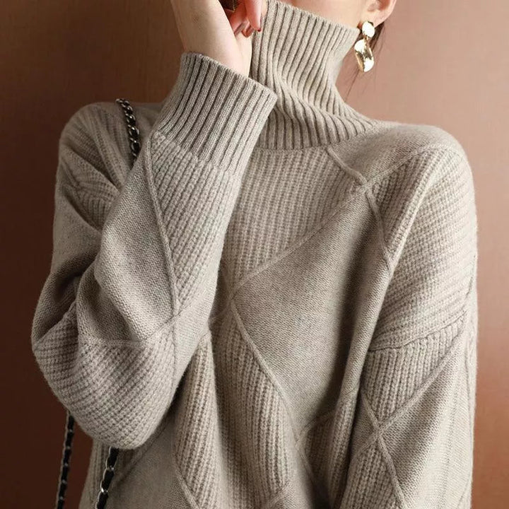 Nahaufnahme eines grauen Strickpullovers mit einem markanten Rautenmuster.