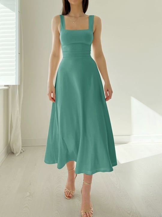 Frau trägt ein ärmelloses Salbei-Midikleid mit tailliertem Oberteil und weitem Rock.